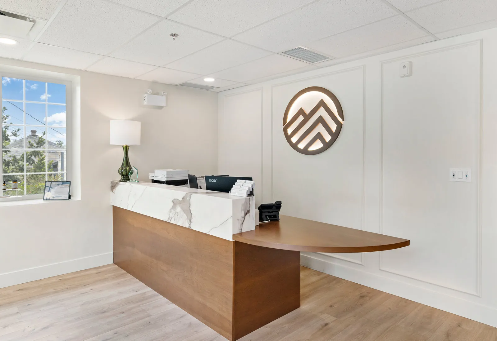 Saanichton Chiropractic Group bright reception with marble-and-wood desk and glowing circular wall logo